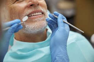 Anciano sonriendo mientras un dentista le revisa los implantes dentales